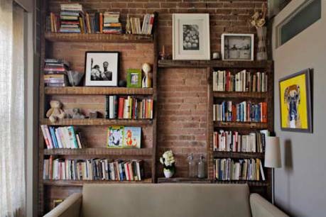 a living room filled with furniture and bookshelves next to a wall covered in pictures