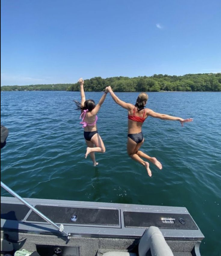 two women jumping into the water from a boat