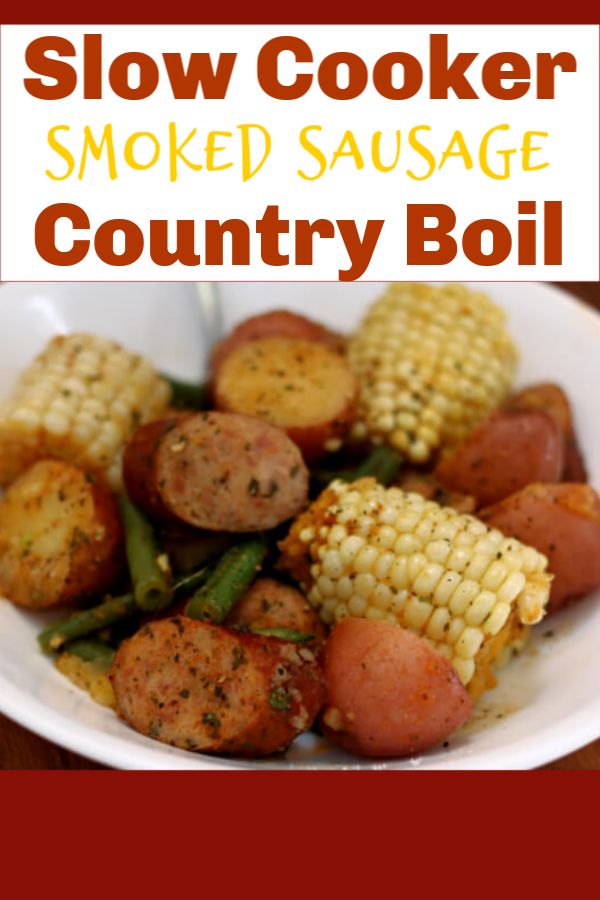 a white bowl filled with meat and corn on the cob next to a wooden table