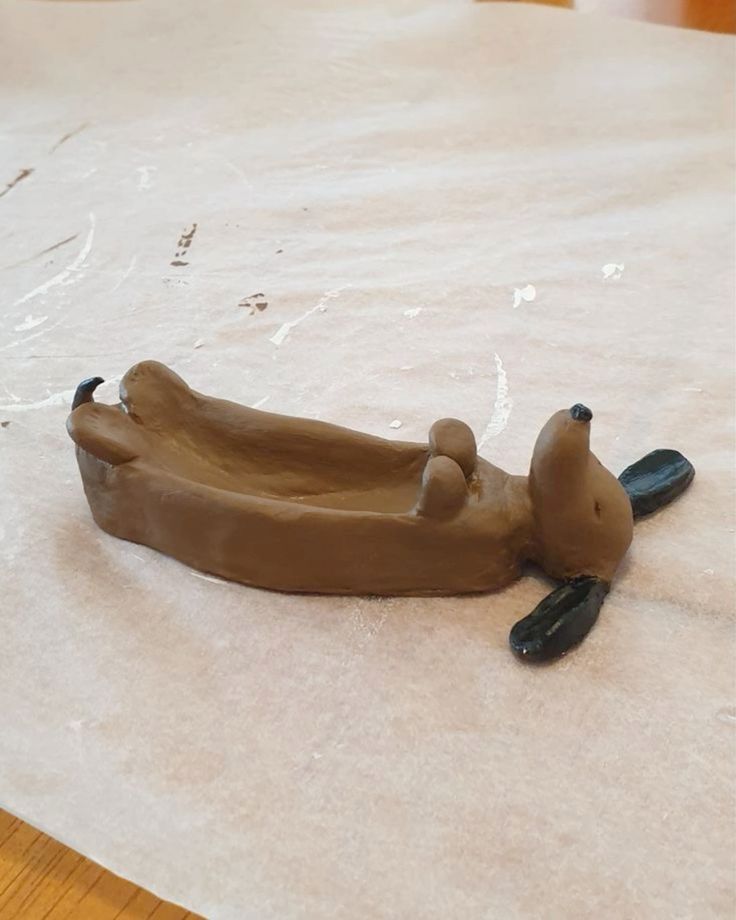 a clay boat shaped like a dog laying on the ground