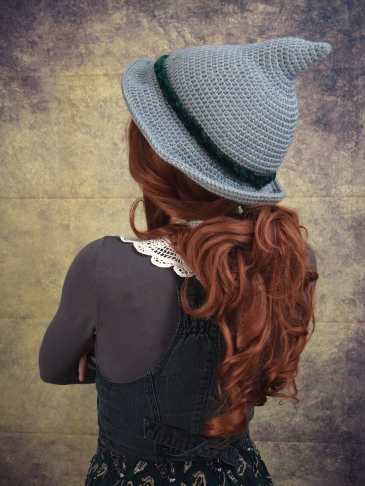 a woman with long red hair wearing a gray crochet hat and black dress