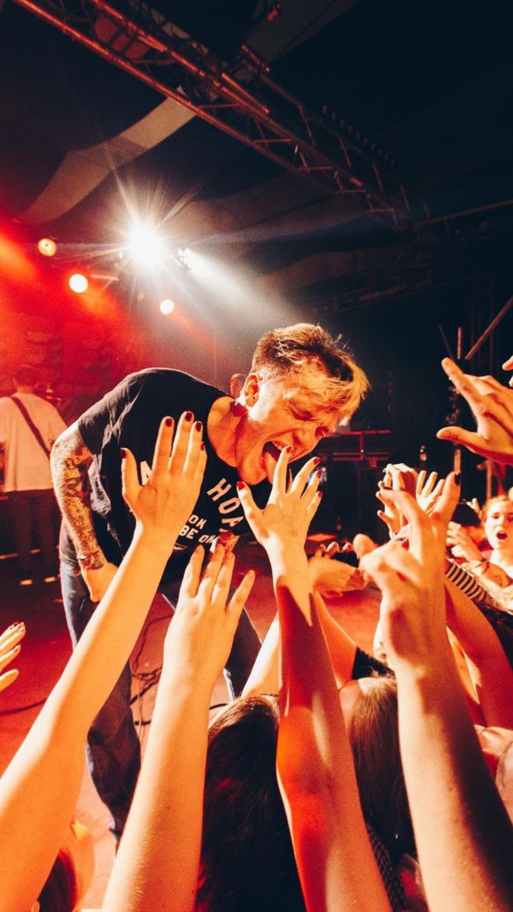 a man standing on top of a crowd of people holding their hands up in the air