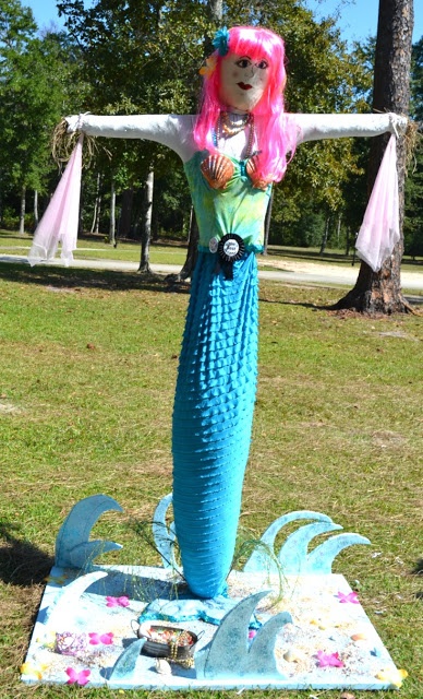 a woman with pink hair standing on top of a blue piece of art in the grass