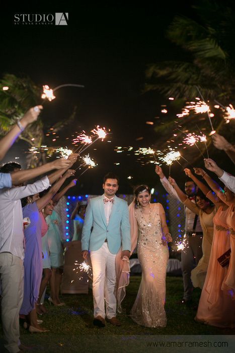 the newly married couple walk down the aisle with sparklers in their hands