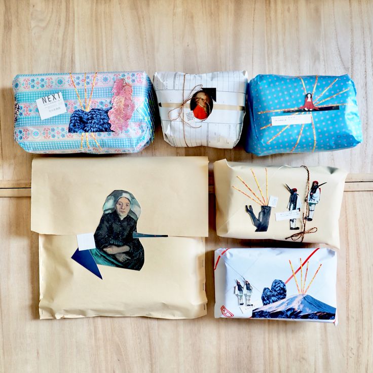 four wrapped presents sitting on top of a wooden table next to an envelope with pictures