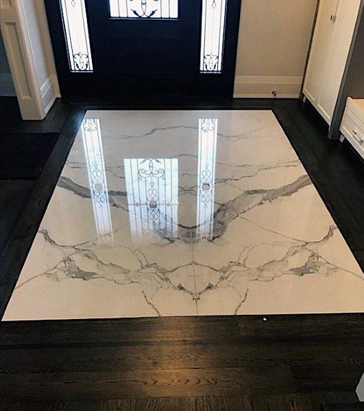 a white marble floor in front of a black door with glass panels on the side