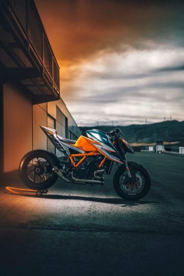 a motorcycle parked in front of a building at night with the sun shining on it