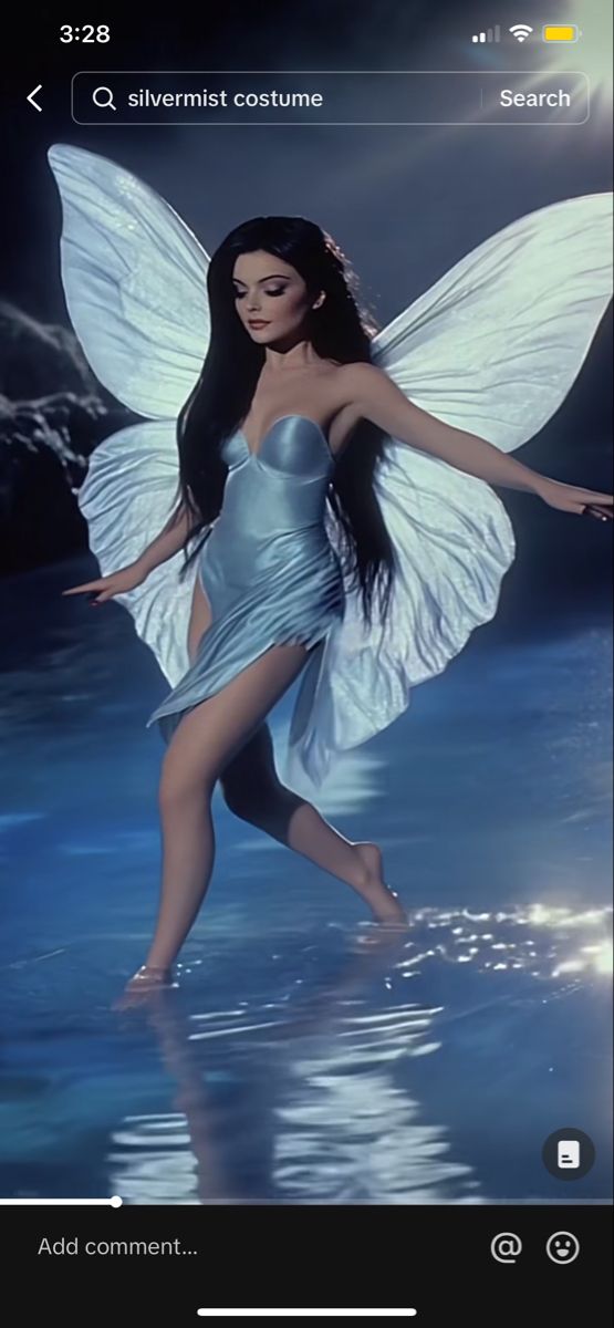 a woman in a silver dress with wings on her body is walking through the water