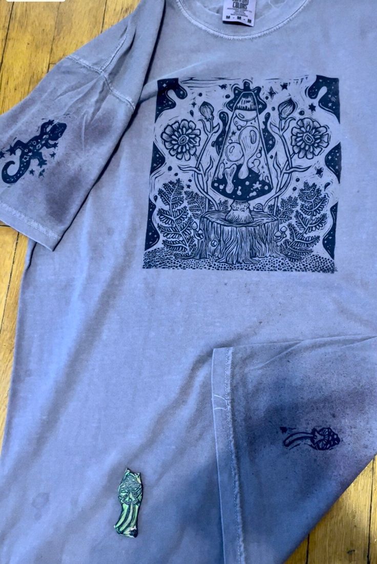 "Dream Scene" is my original linocut print and design. I hand stamp my groovy block on t-shirts to walk around and spread the good vibes. This shirt not only features the dreamy lava lamp mushroom design on the front, but also a salamander on the sleeve and another little mushroom on the back. These are also my original linocuts. These are printed on Comfort Color "Grape" color t-shirts. These shirts are a cozy fit and 100% cotton. Since these are hand printed, all shirts vary slightly. Unisex Festival T-shirt With Screen Print, Festival T-shirt With Screen Print And Relaxed Fit, Hippie Style Relaxed Fit Screen Print T-shirt, Hippie Style Relaxed Fit T-shirt With Screen Print, Unisex Screen Print T-shirt For Festival, Hippie Style Screen Print T-shirt For Festival, Hippie Style Festival T-shirt With Screen Print, Block Tshirt, Lamp Mushroom