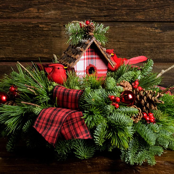 a birdhouse decorated with pine cones, red berries and evergreen needles sits on a table