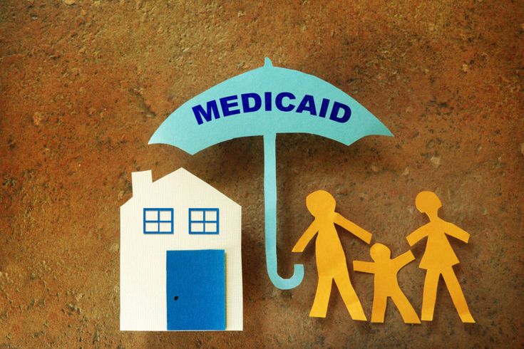 paper cutouts of people holding hands under an umbrella with the word medicaid above them