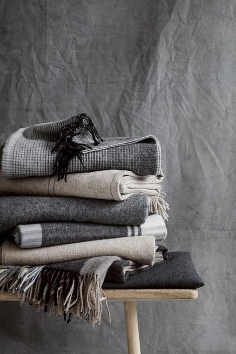 a stack of folded towels on top of a wooden table next to a gray wall