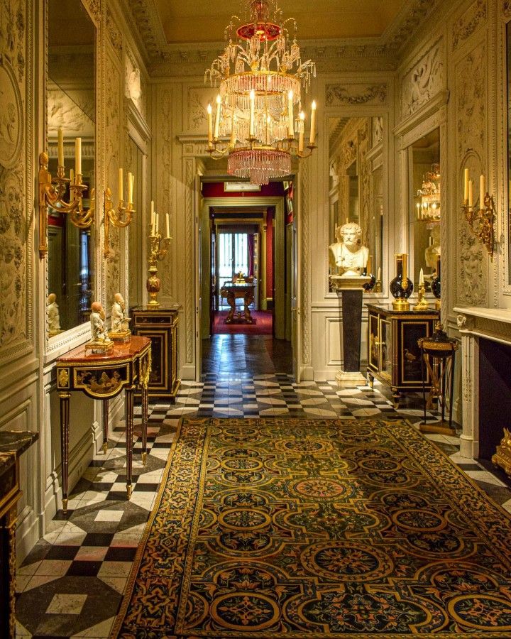 an ornate hallway with chandelier and marble flooring is seen in this image