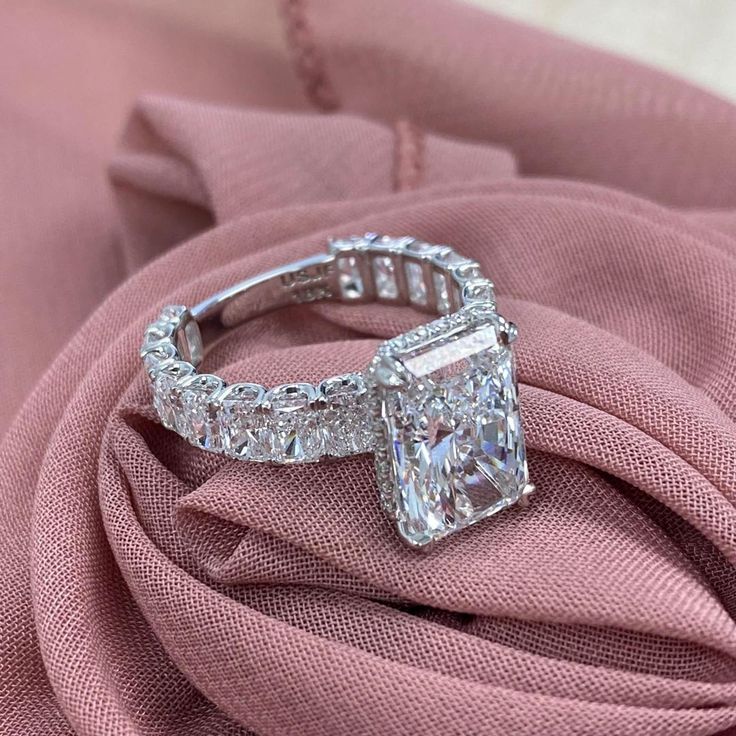 an engagement ring on top of a pink cloth with diamonds in the center and sides