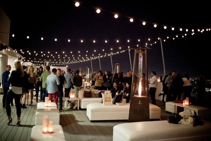 a group of people standing on top of a wooden floor next to white couches