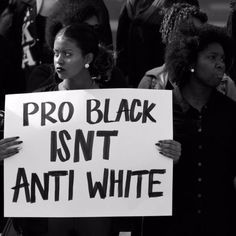 people holding signs that read pro black isn't anti white