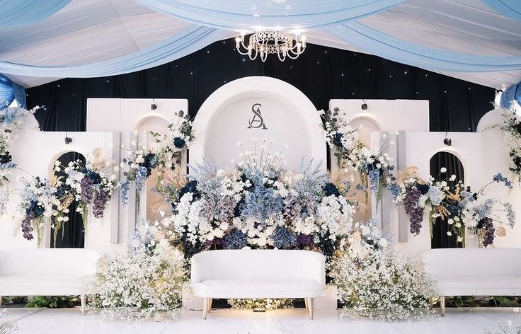 a white couch sitting in front of a blue and white backdrop with flowers on it