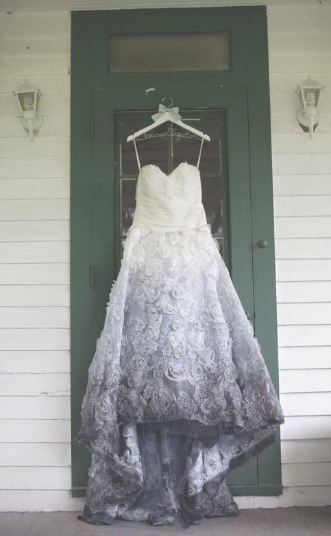 a wedding dress hanging on the front door of a white house with green trimmings