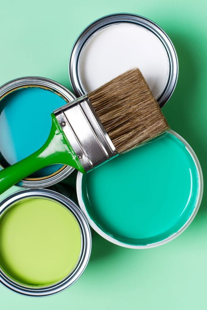 two paint cans with one green and the other blue on top of it, next to a brush