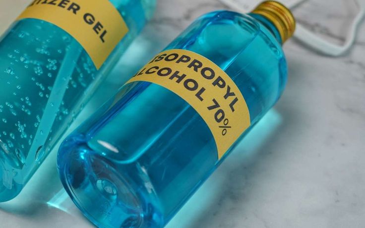 two blue bottles with yellow labels on them sitting next to each other, one containing water gel and the other containing alcohol