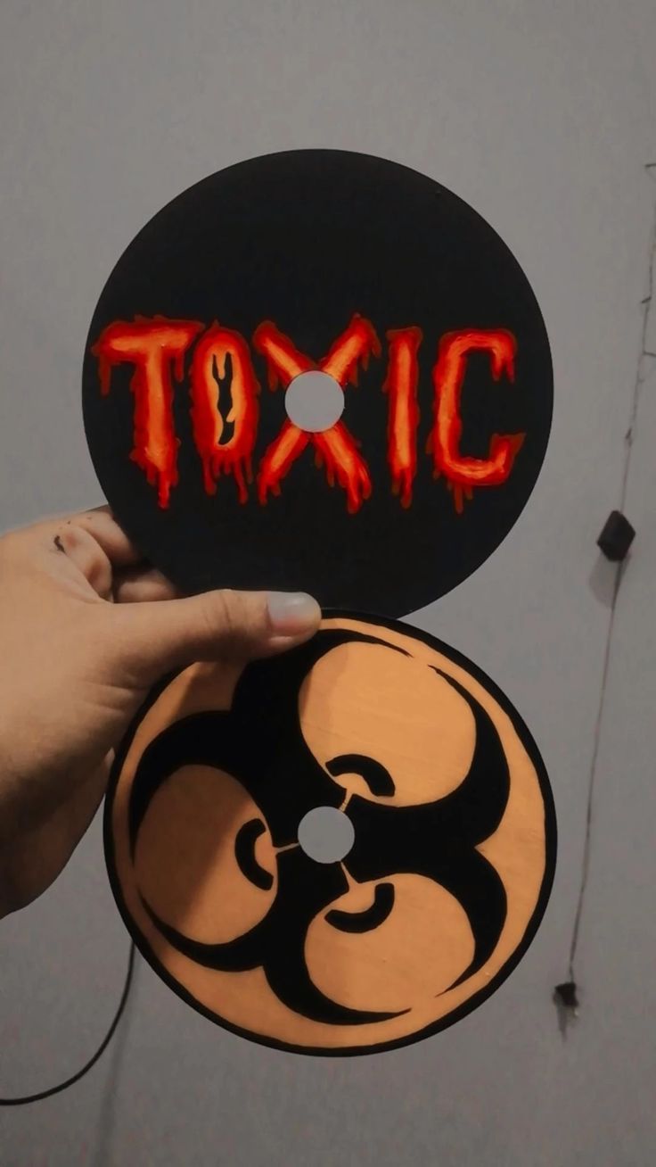 a person holding up a sticker with the word toxic painted on it