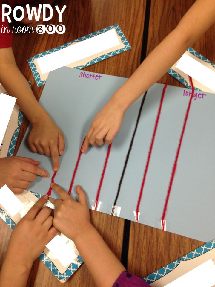 two children are making something out of construction paper and stringing it on the table