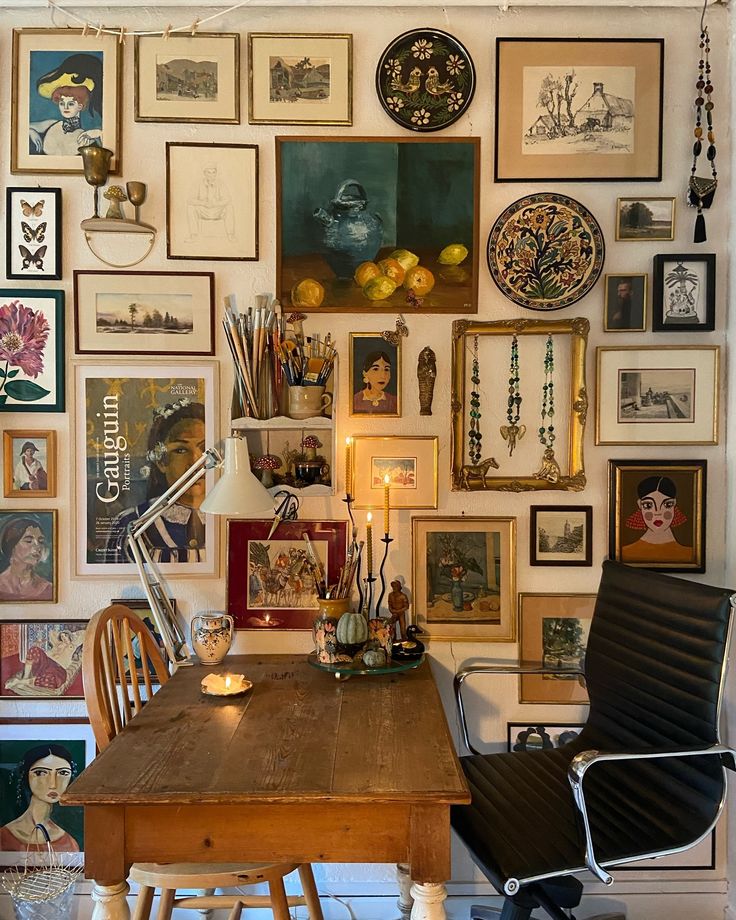 a wooden table sitting in front of a wall filled with pictures and art on it