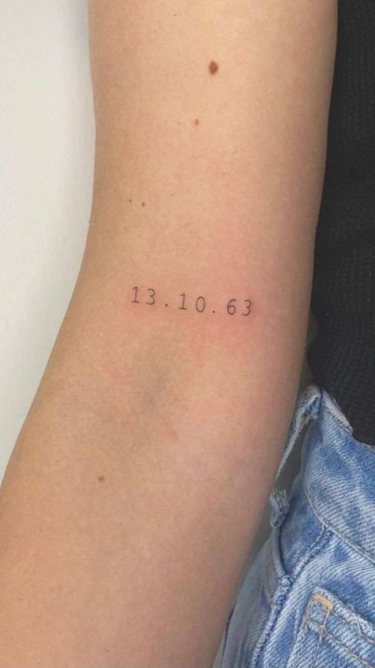 a person with a small tattoo on their arm that reads 13 01 53 and has the date