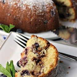 a close up of a muffin on a plate with blueberries and mint leaves