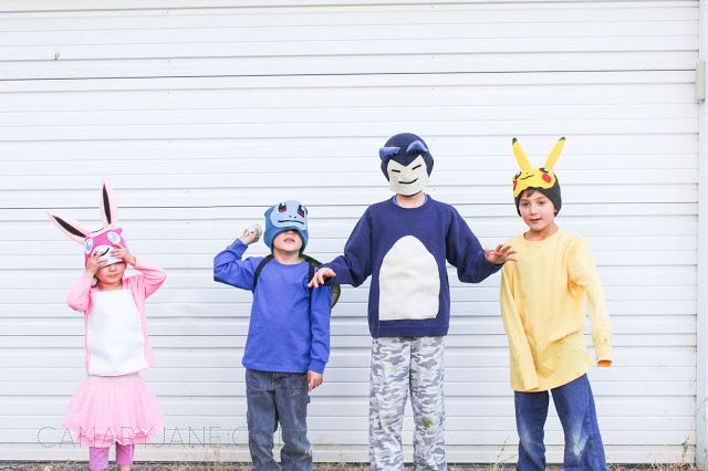 three children wearing animal masks standing in front of a garage door with their hands up