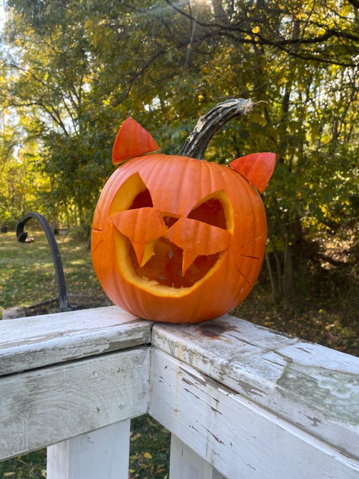 a carved pumpkin sitting on top of a wooden fence