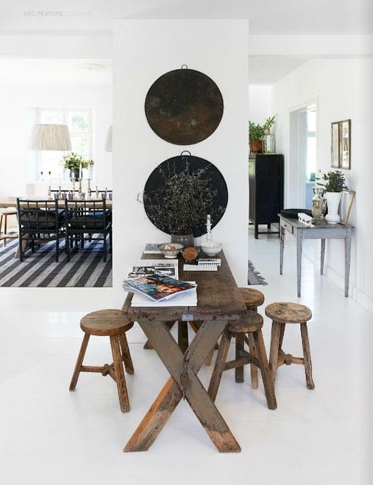 the dining room table is surrounded by stools and round metal plates on the wall