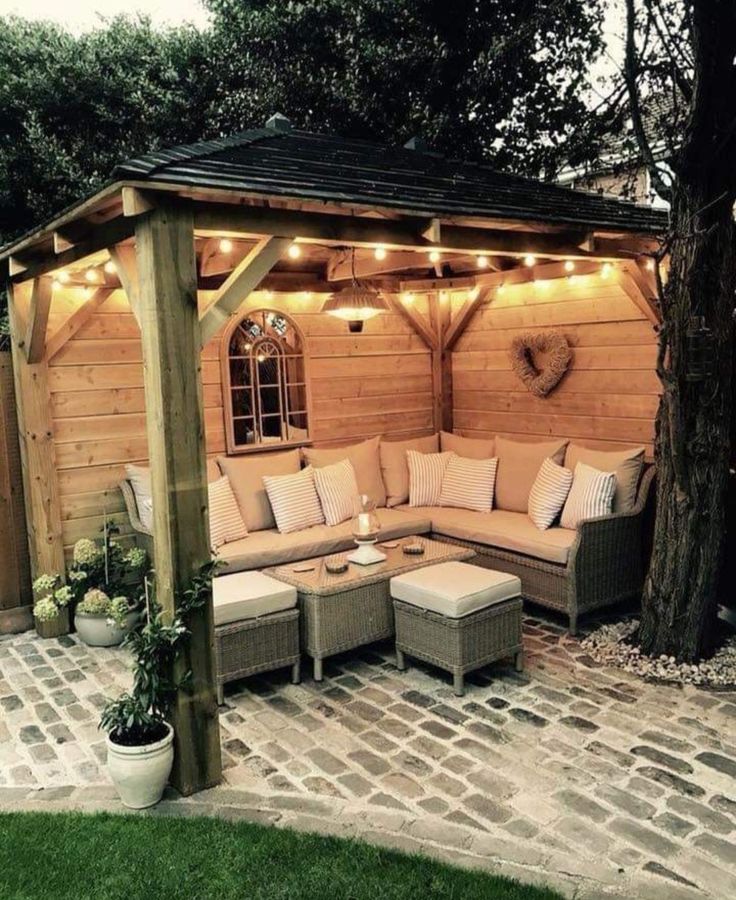 an outdoor living area with couches and lights on the roof, surrounded by brick pavers