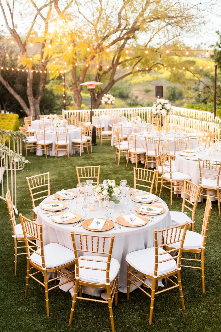 an outdoor wedding reception setup with tables and chairs