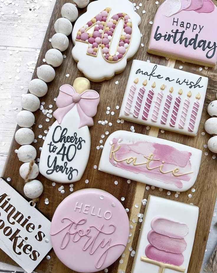 cookies decorated with pink and white icing are on a wooden board next to other decorations