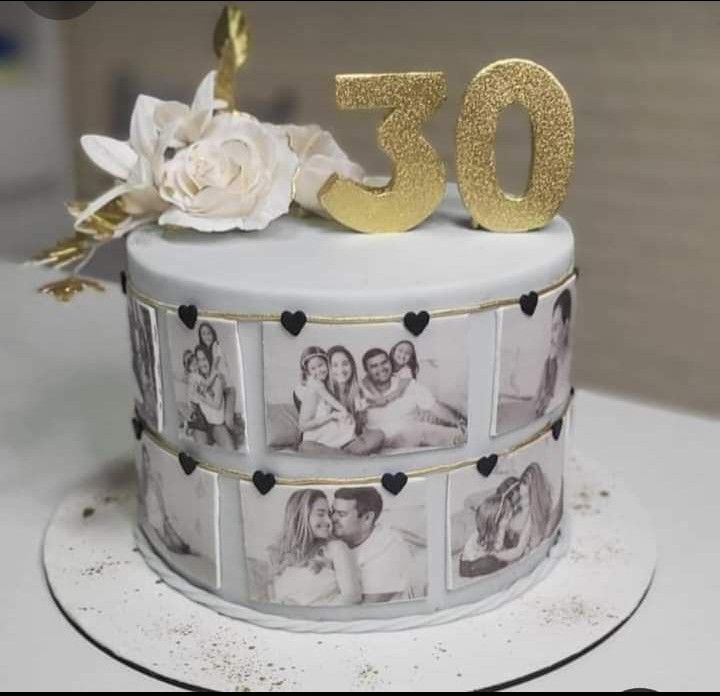 a white cake with gold numbers and photos on it's side, decorated with flowers