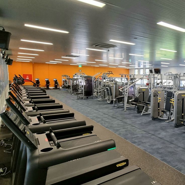 an empty gym with rows of treadmills and machines