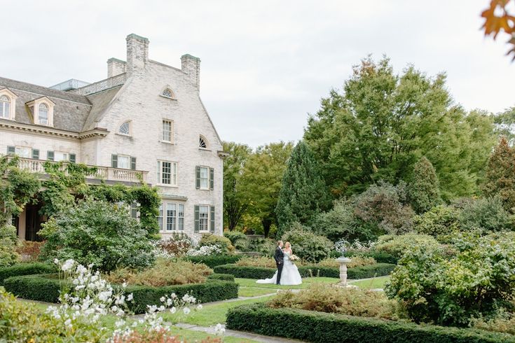 a bride and groom standing in front of a large house