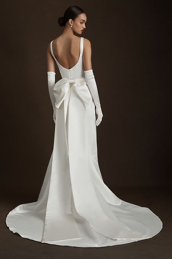 the back of a woman's wedding dress, with her hands on her hips