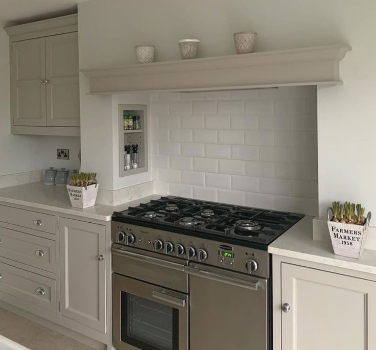 a stove top oven sitting inside of a kitchen next to white cupboards and drawers