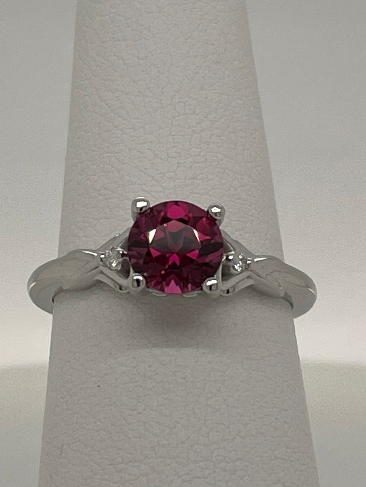 This natural round Rhodolite Garnet is 1.45ct purplish red and set in a 14K white gold ring size 7 (sizable) with .02ctw VS G-H Diamond Melee.  Each side of the ring as a heart-shape with a 1.4mm diamond set inside.  The name Rhodolite is derived from the Greek "rhodon" for "rose-like".  This stone has great color, cut and clarity. Garnet is the birthstone for the month of January. I am a GIA Graduate Gemologist with a passion for all gemstones.  I have a 30 day return policy so if do not wish to keep this item, simply return to me for your refund. Clarity        Eye-Clean Carat Weight1.45 carats Shape         Round Cut                Step Cut Enhancement (N) None  Gemstone Enhancement Codes*  N = Not Enhanced B = Bleaching C = Coating  D = Dyeing F = Filling H = Heating  HP = Heat & Press Garnet Birthstone Ring With Prong Setting, Lab-created Ruby Diamond Ring With Prong Setting, Ruby Rings With Diamond Cut, Round Ruby Rings With Diamond Cut, White Gold Ruby Ring With Center Stone, Classic Red Sapphire Ring, Lab-created Ruby Diamond Ring With Accent Stones, Red Round Solitaire Sapphire Ring, Red Solitaire Sapphire Ring