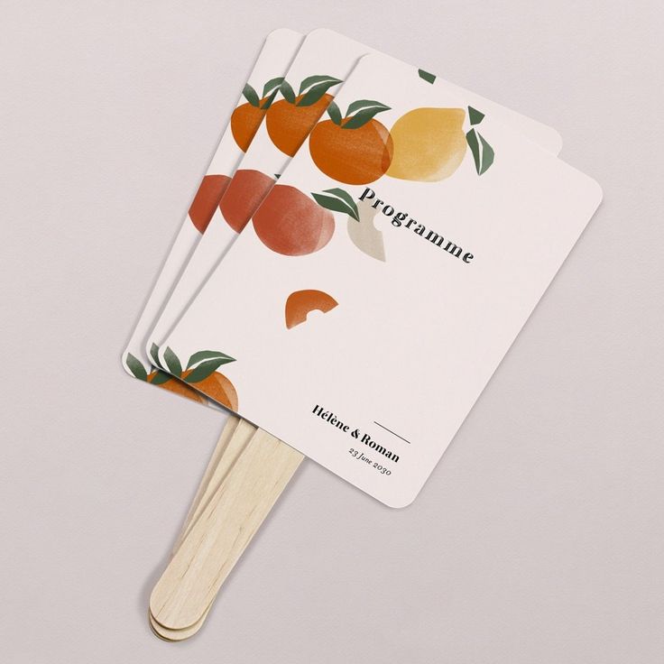 three oranges on top of each other with wooden sticks in front of the card