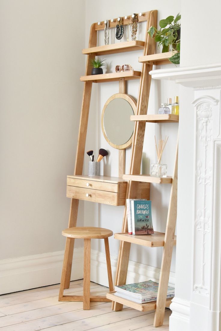 a wooden ladder shelf next to a mirror on top of a white rug in a room