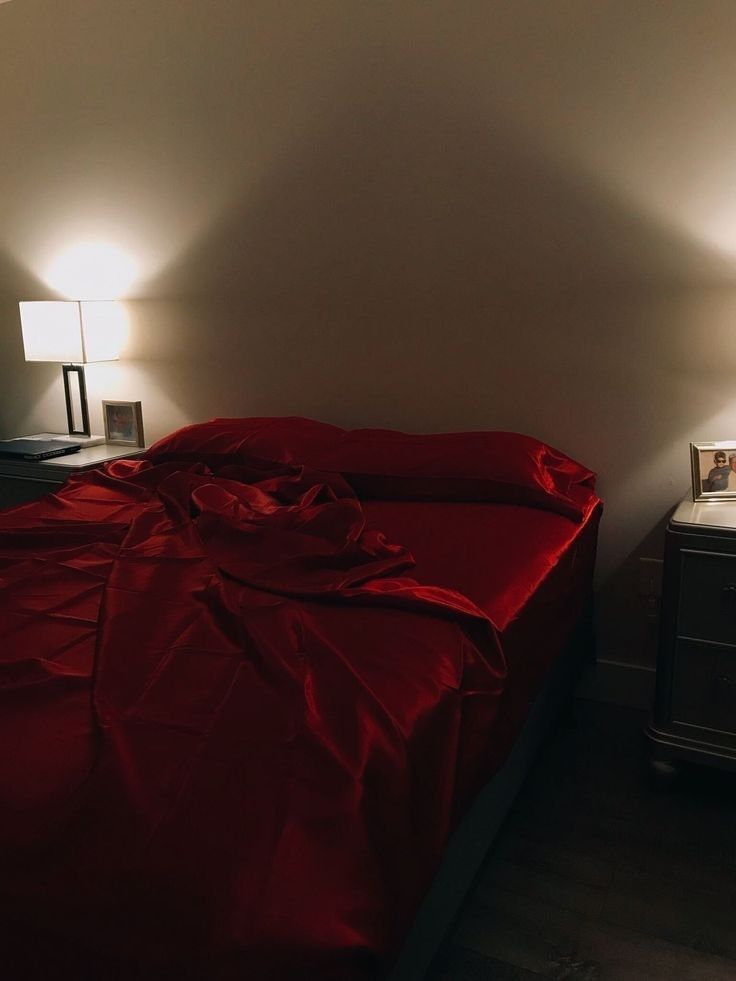 a bed with a red comforter and two lamps