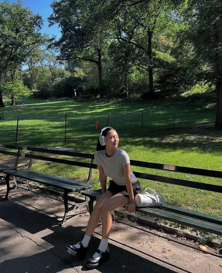 a woman is sitting on a bench in the park