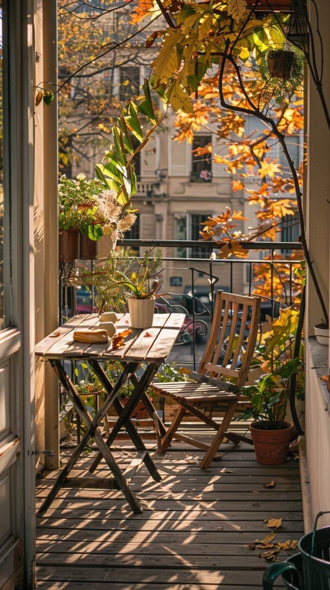 an outdoor table and chairs on a porch with autumn leaves in the window sill