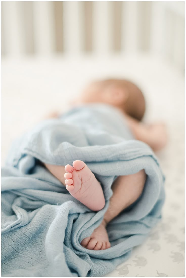 a baby wrapped in a blanket on top of a bed