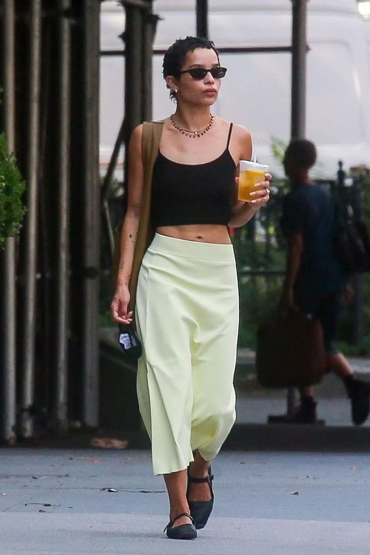 a woman walking down the street with a drink in her hand