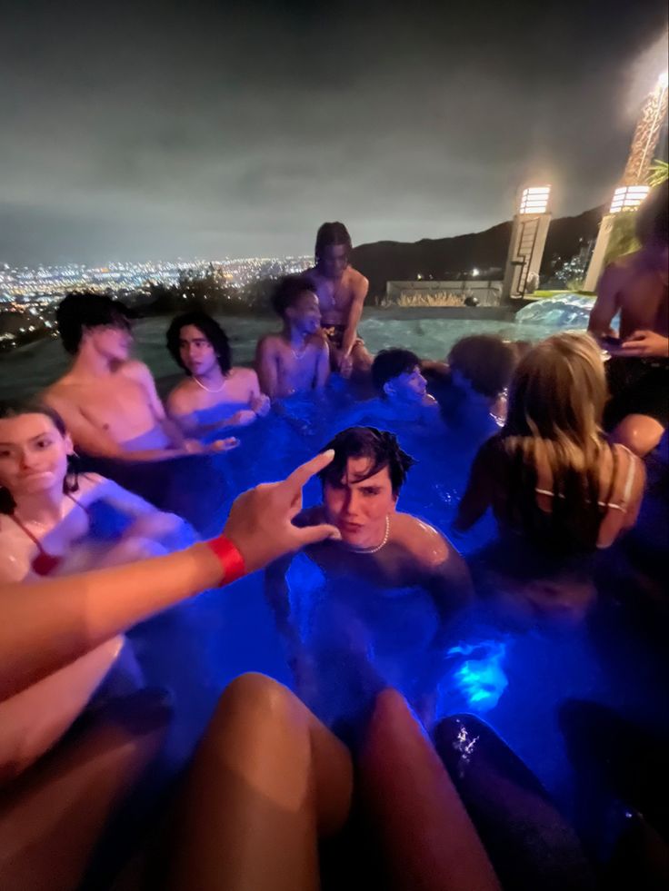 a group of people sitting in a hot tub with the city lights in the background