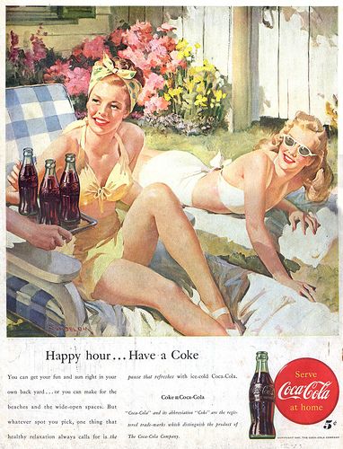 two women in bathing suits sitting on a lawn chair with bottles of beer next to them